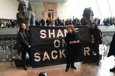 Nan Goldin standing in front of black protest sign