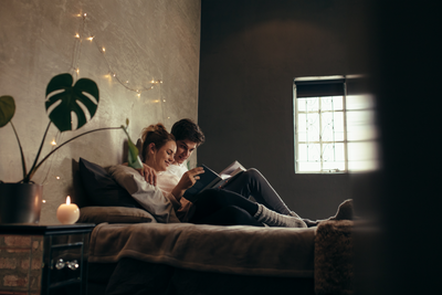 young couple on a bed reading a book